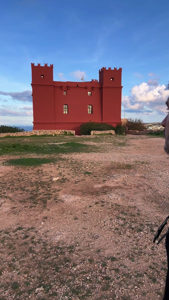 Exploring Malta ❤️ Hiking the Red Tower 🇲🇹🌍 Saint Agatha's Tower sits atop l-Aħrax tal-Mellieħa at the edge of the Marfa ridge, overlooking Għadira Bay and the islands of Comino and Gozo in the distance. 🤩 The tower was painted red by the Knights of St. John so it could be recognized from other towers in the same eye line. It was constructed over 2yrs and was finished in 1649. 📚 It stands as part of a defensive strategy built all along the coastline of the Maltese islands, used as intimidation and communication with other towers. 🔥 The tower can defend itself with cannons as well as supplies to last up to 40 days of a siege. Normally housing 4 local militia members, it can be reinforced by up to 50 extra soldiers in the case of incursion. It was also manned by the British in both World Wars. 😳 The hike is a little under 4km (2.5 miles) one way, and takes anout an hour from the Mellieħa parish church. You can also get there from Paradise Bay, Ċirkewwa, or the Chapel of Immaculate Conception on the northeast tip of the island.